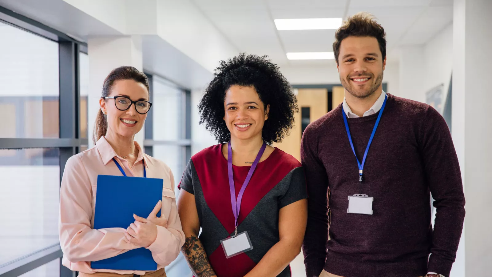 three educators in a school hallway, two women and one man.