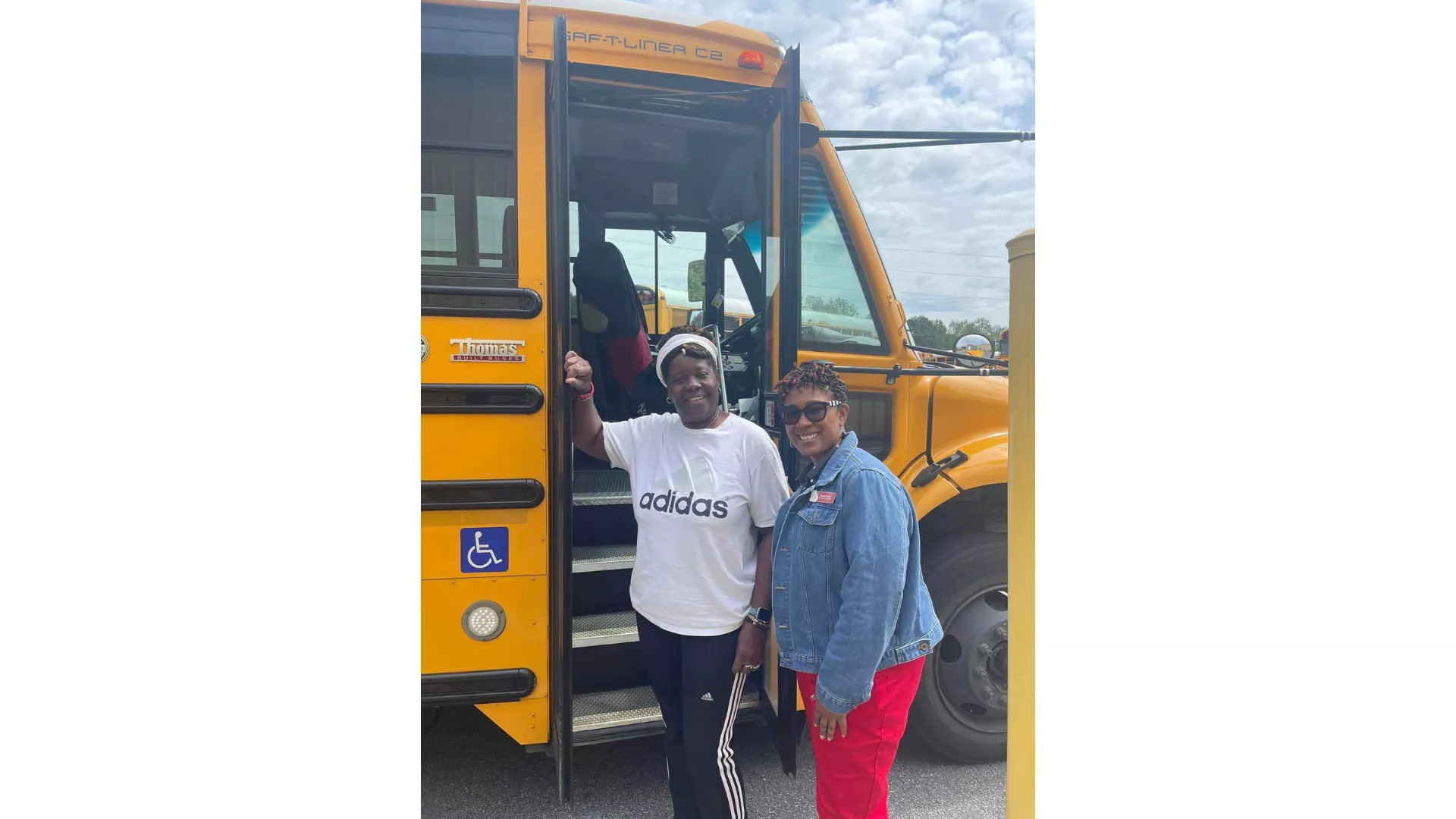 two educators in front of a bus